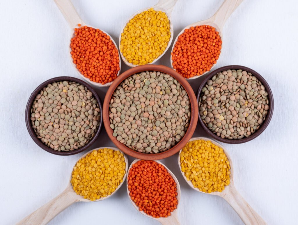 top view different lentils in brown bowls and wooden spoons on white background. horizontal